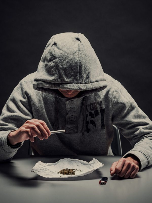 A drug addict makes a cigarette with marijuana. The concept of drug abuse and traffic